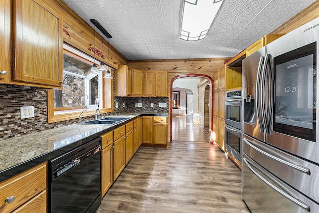 kitchen featuring hanging light fixtures, sink, dark wood-type flooring, decorative backsplash, and stainless steel appliances