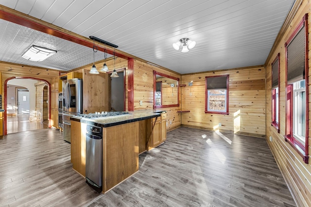 kitchen with kitchen peninsula, wood walls, pendant lighting, and dark hardwood / wood-style floors