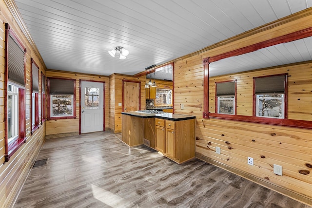 kitchen featuring wood-type flooring, wooden walls, kitchen peninsula, and pendant lighting