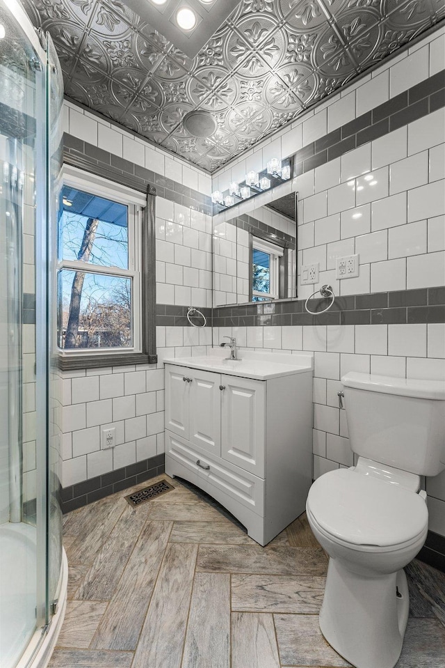 bathroom with walk in shower, toilet, vanity, and tile walls