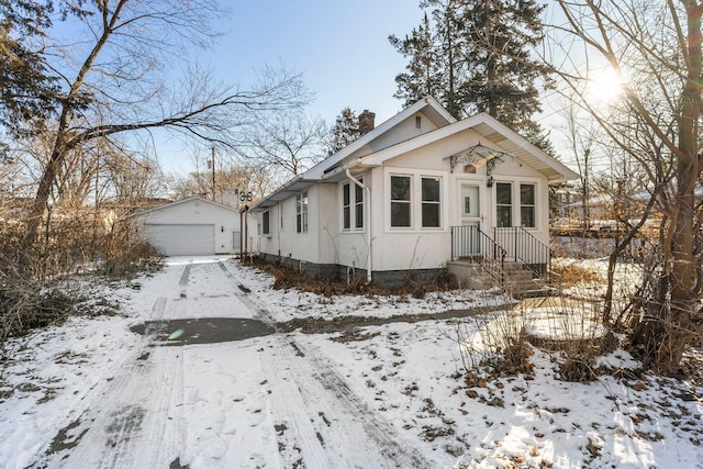 bungalow-style house with a garage and an outdoor structure