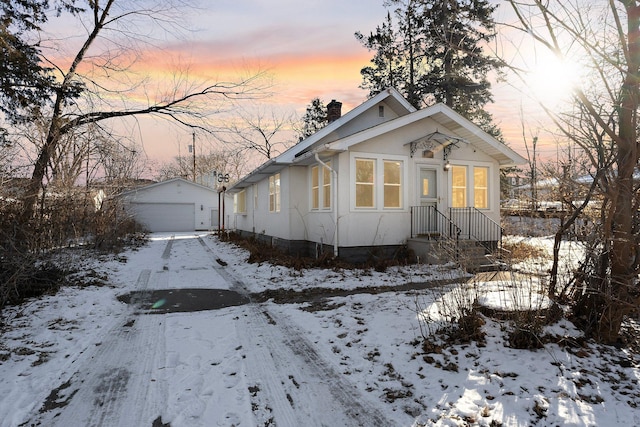 bungalow-style house featuring a garage and an outbuilding