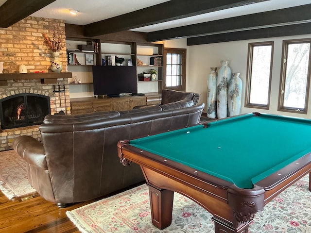 recreation room featuring hardwood / wood-style floors, beam ceiling, a fireplace, and pool table