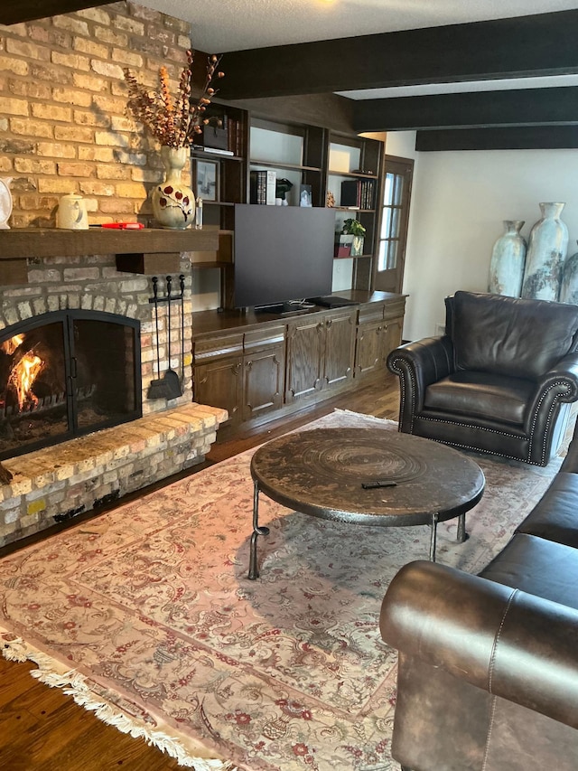 living room featuring hardwood / wood-style floors, beam ceiling, and a fireplace