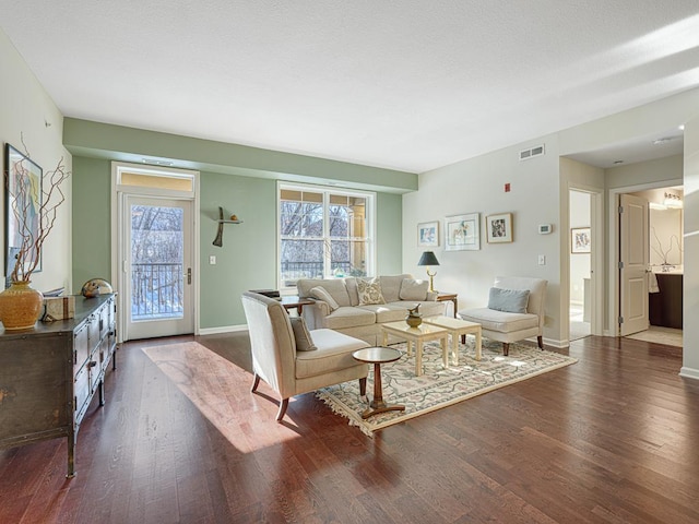 living room with visible vents, baseboards, and dark wood finished floors