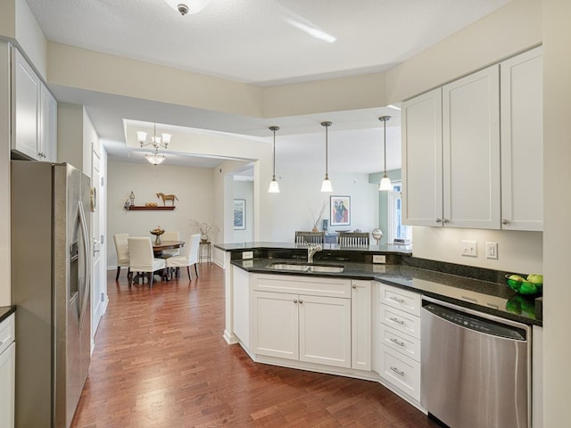 kitchen featuring stainless steel appliances, a sink, white cabinetry, dark wood-style floors, and pendant lighting