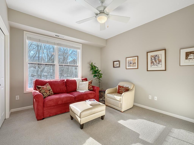 living room with baseboards, visible vents, a ceiling fan, and light colored carpet