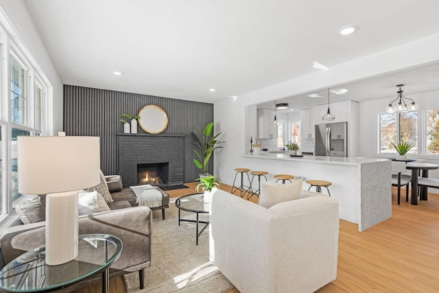 living room featuring a brick fireplace and light wood-type flooring