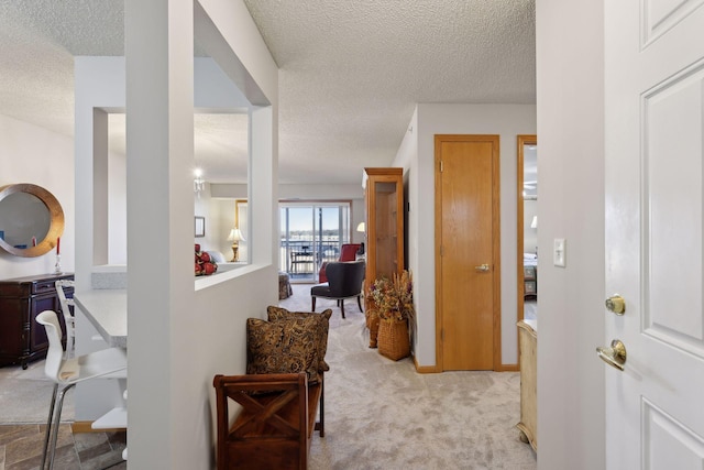 corridor featuring light colored carpet and a textured ceiling