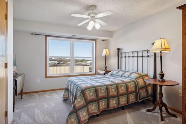 bedroom with a textured ceiling, carpet floors, and ceiling fan