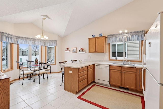 kitchen featuring decorative light fixtures, lofted ceiling, sink, kitchen peninsula, and white appliances