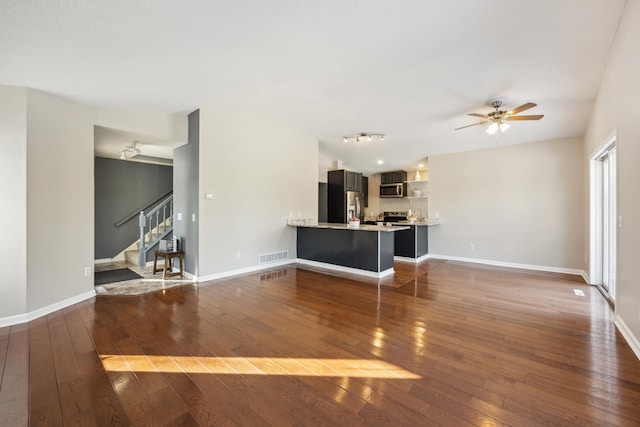 unfurnished living room with baseboards, visible vents, lofted ceiling, dark wood-style flooring, and stairs