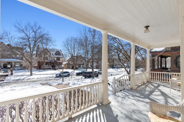 snow covered deck featuring a porch