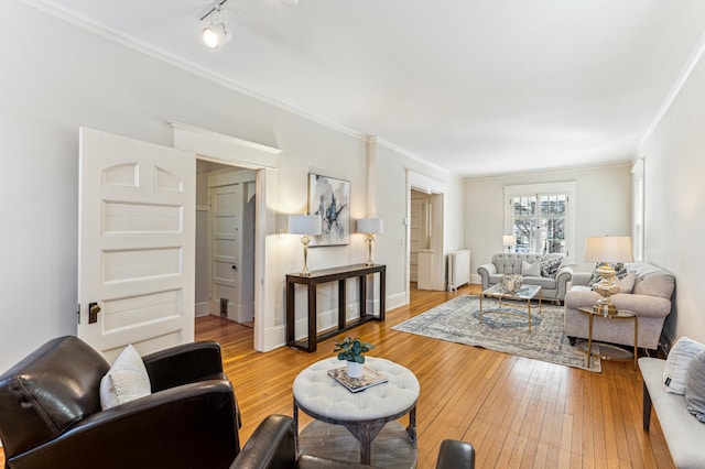 living room with radiator, crown molding, baseboards, and wood-type flooring