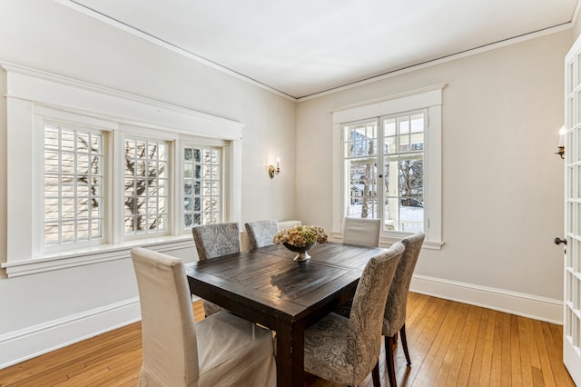 dining room with light wood-type flooring, baseboards, and ornamental molding