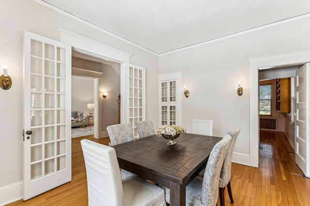 dining space with baseboards, light wood-type flooring, and ornamental molding