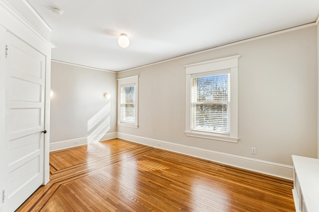 spare room with light wood-style flooring, crown molding, and baseboards