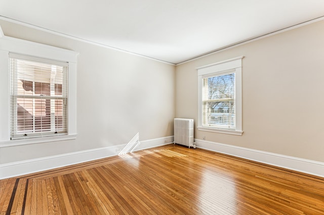 spare room with hardwood / wood-style flooring, radiator, baseboards, and ornamental molding