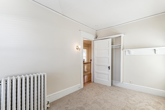 unfurnished bedroom with a closet, baseboards, radiator, and carpet