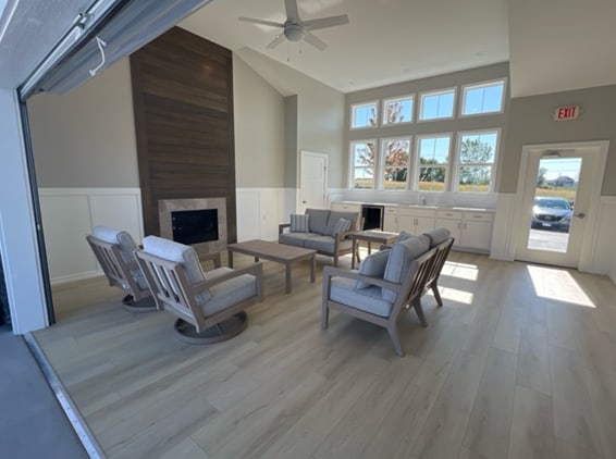 living room with light hardwood / wood-style floors, ceiling fan, a fireplace, wine cooler, and vaulted ceiling