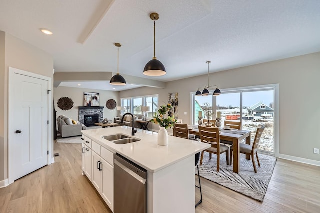 kitchen with an island with sink, dishwasher, pendant lighting, white cabinets, and sink