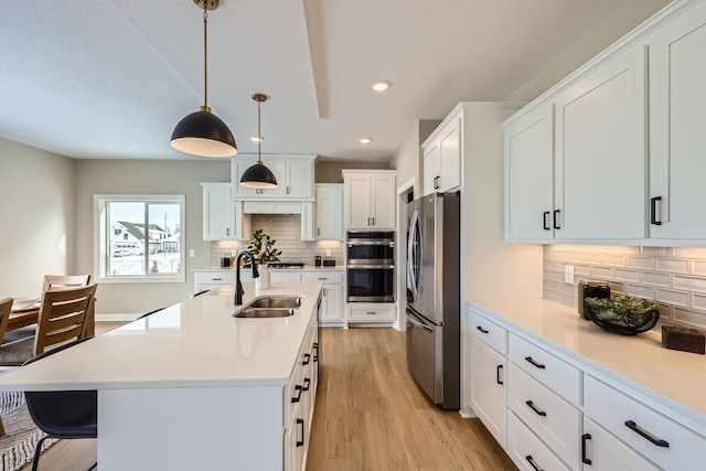 kitchen featuring white cabinets, decorative light fixtures, stainless steel appliances, decorative backsplash, and sink