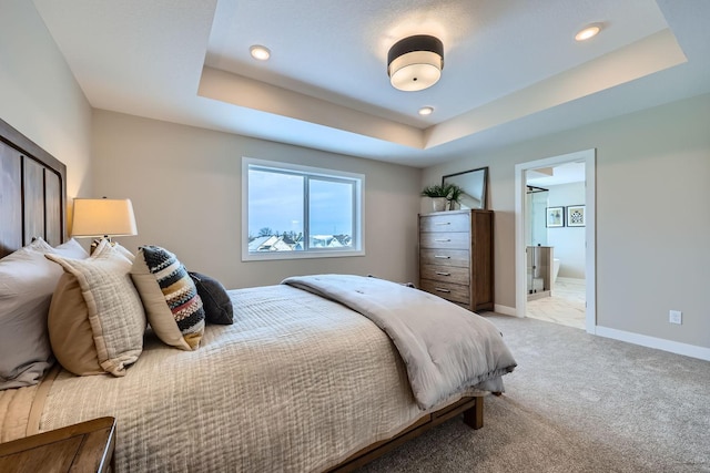 carpeted bedroom with ensuite bathroom and a tray ceiling