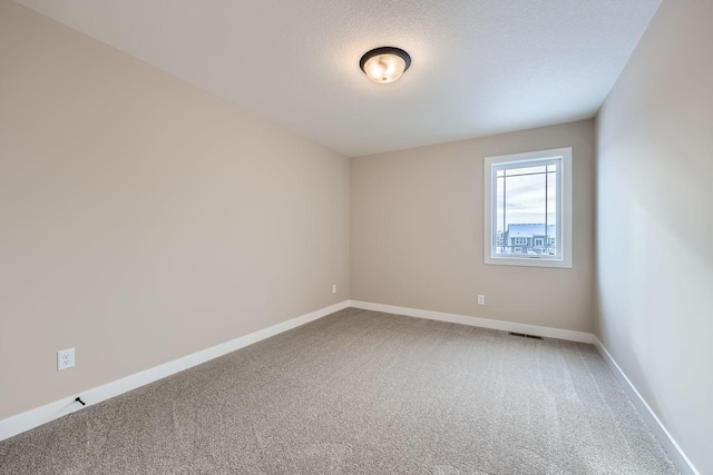 carpeted empty room featuring a textured ceiling