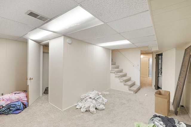 basement featuring a drop ceiling and light carpet