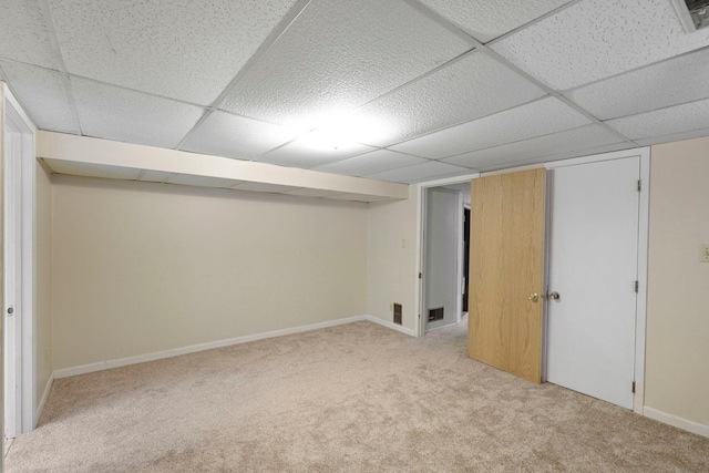 basement featuring a drop ceiling and light carpet