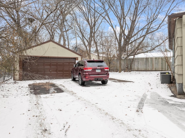 yard covered in snow featuring a garage, central AC, and an outdoor structure