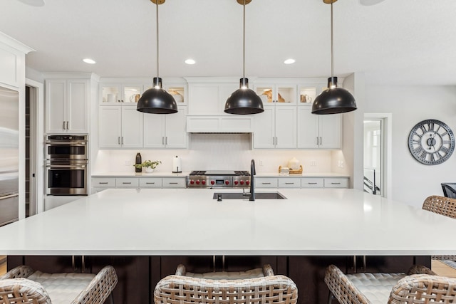 kitchen featuring a breakfast bar, double oven, sink, white cabinets, and a spacious island