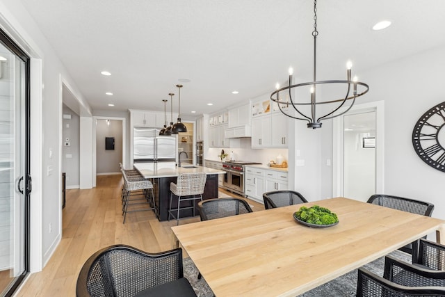 dining room featuring sink, a chandelier, and light hardwood / wood-style floors