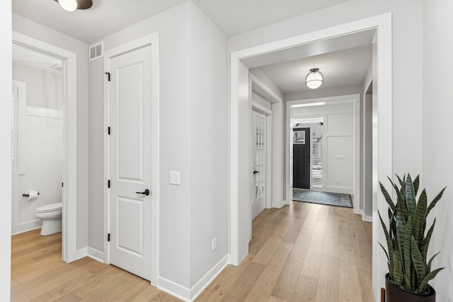 hall with light hardwood / wood-style floors and a textured ceiling