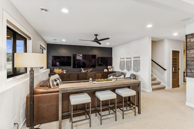 kitchen with ceiling fan, light colored carpet, wooden counters, and a breakfast bar area