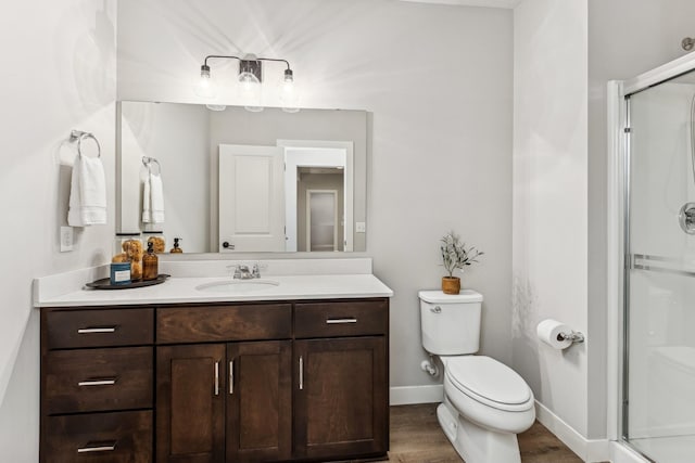 bathroom with vanity, hardwood / wood-style flooring, a shower with shower door, and toilet