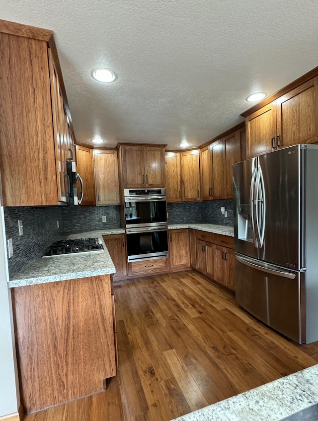 310 7th St SW, Roseau, MN 56751 - kitchen with brown cabinetry, a textured ceiling, dark wood-style flooring, and stainless steel appliances