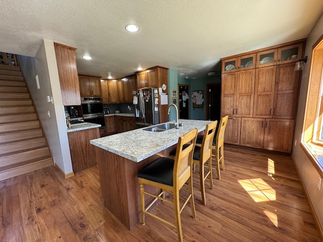 310 7th St SW, Roseau, MN 56751 - kitchen featuring a textured ceiling, light wood finished floors, refrigerator with ice dispenser, and a sink