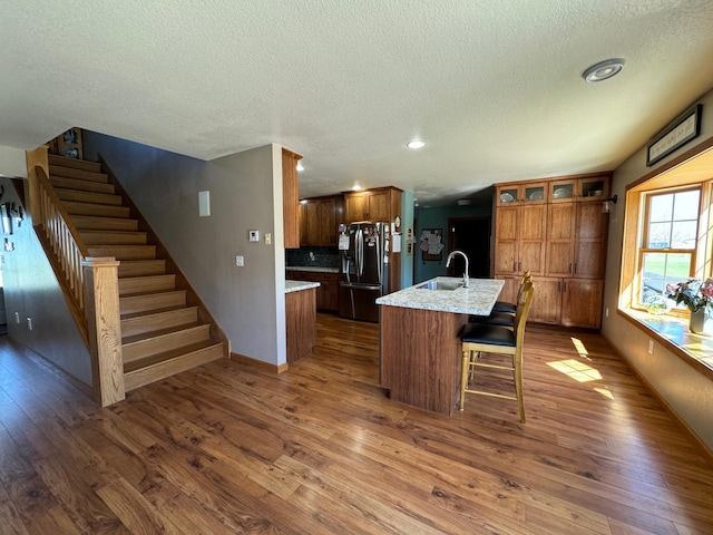 310 7th St SW, Roseau, MN 56751 - kitchen featuring a textured ceiling, brown cabinets, a sink, dark wood-style flooring, and stainless steel refrigerator with ice dispenser