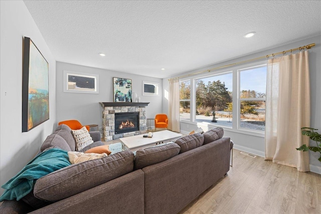 living room featuring a fireplace, light hardwood / wood-style flooring, and a textured ceiling