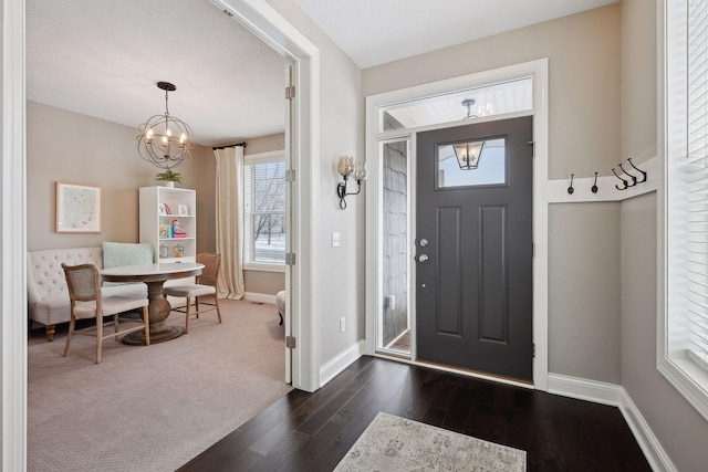 foyer entrance featuring dark wood-style floors, baseboards, and an inviting chandelier