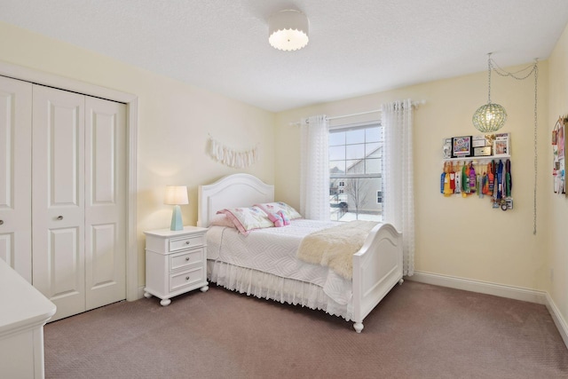 bedroom with baseboards, a textured ceiling, dark carpet, and a closet