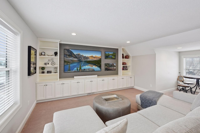 living area featuring built in shelves, light colored carpet, a textured ceiling, and baseboards