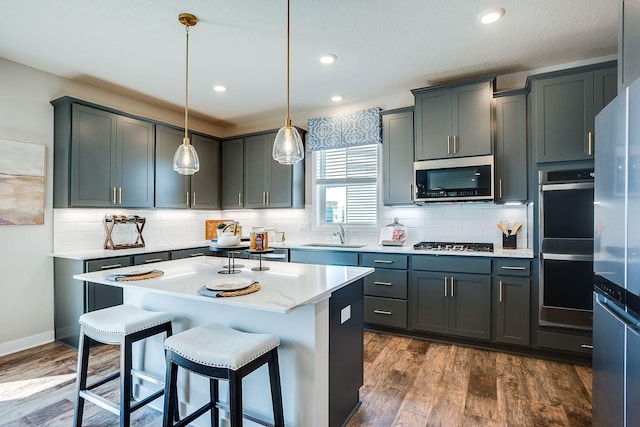 kitchen with pendant lighting, a center island, dark wood-type flooring, gray cabinets, and appliances with stainless steel finishes