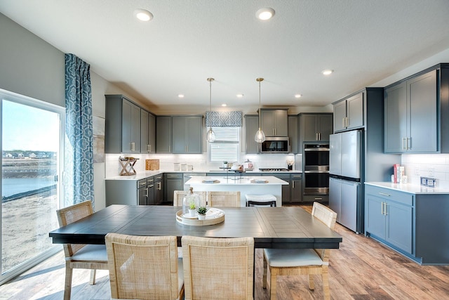 kitchen with tasteful backsplash, a center island, stainless steel appliances, and decorative light fixtures