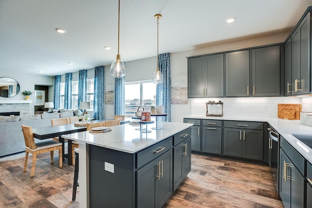 kitchen featuring a center island, gray cabinets, a stone fireplace, and hanging light fixtures