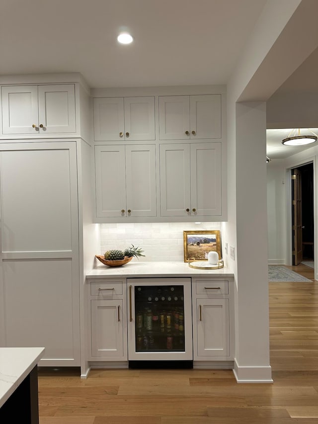 bar with white cabinetry, decorative backsplash, light hardwood / wood-style floors, and beverage cooler