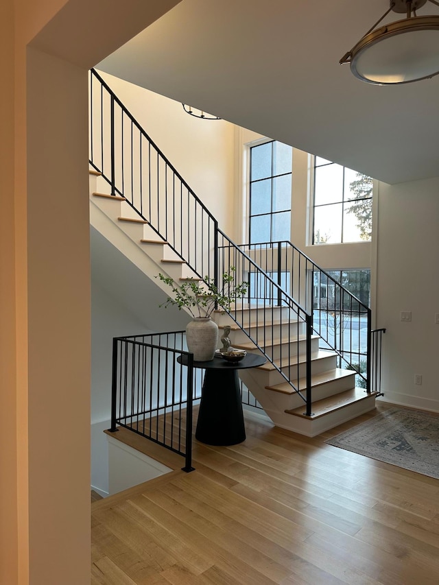 staircase with a high ceiling and wood-type flooring