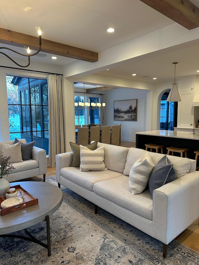 living room featuring hardwood / wood-style flooring, beam ceiling, and a chandelier