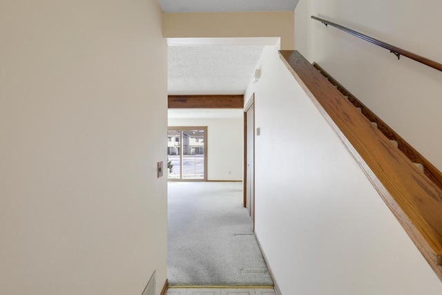 stairway with beamed ceiling, carpet floors, and a textured ceiling